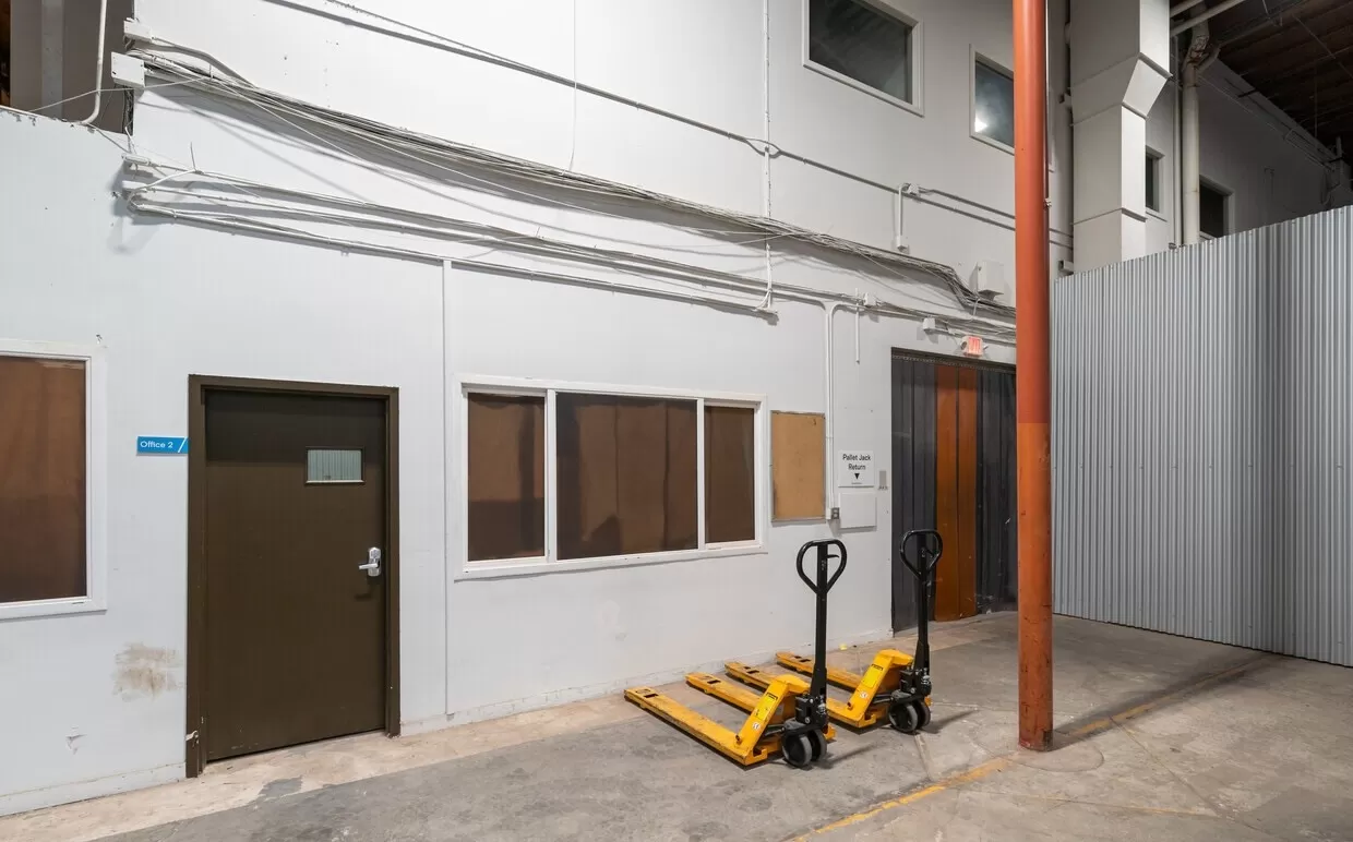A storage room in a Hayward warehouse space with a yellow forklift and a door.
