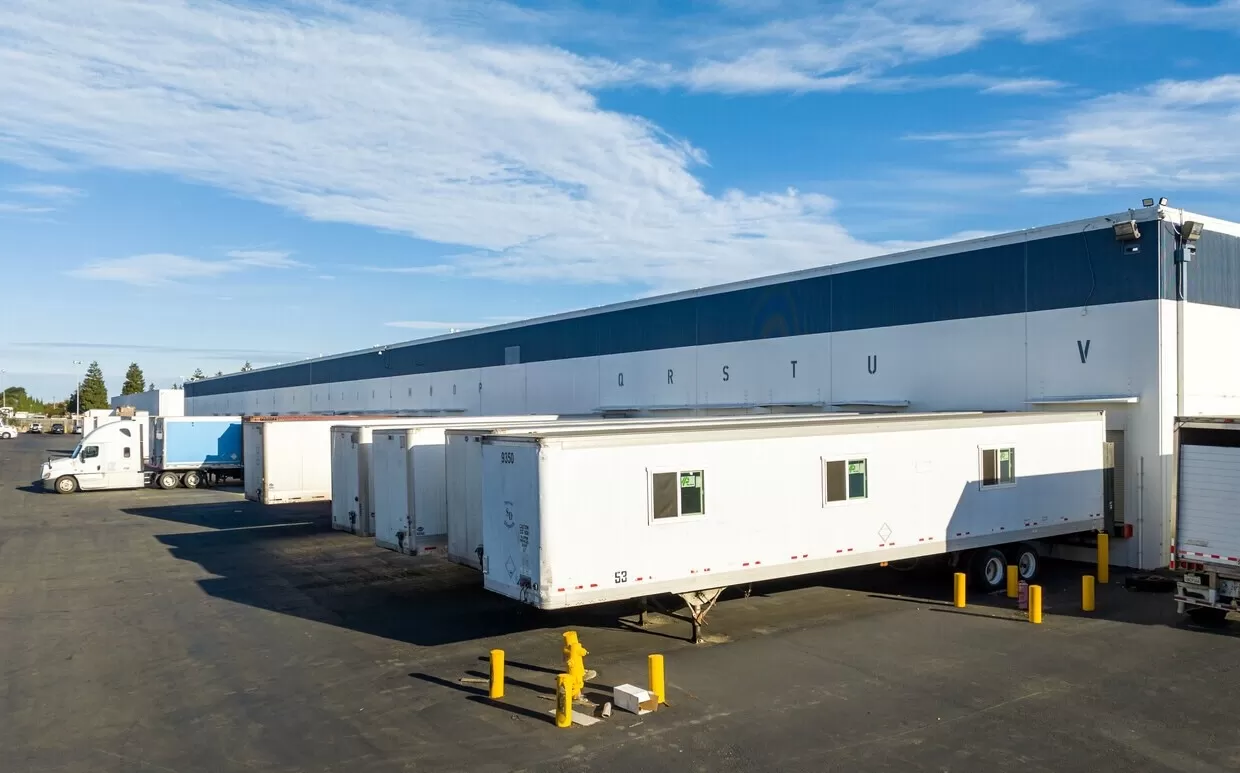 A spacious warehouse in Hayward with trucks parked in front of it.