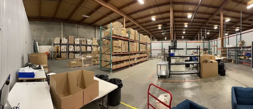 A warehouse for shipping and distribution with many boxes and chairs.