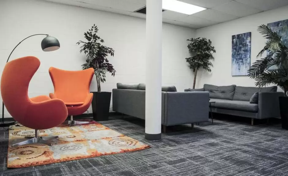 An office with orange chairs and a rug.