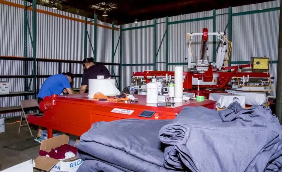 Two men working in a warehouse with a lot of clothes.