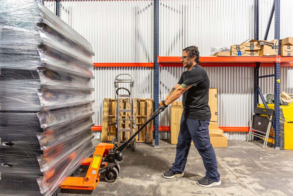 A man pushing a pallet of boxes in a warehouse.