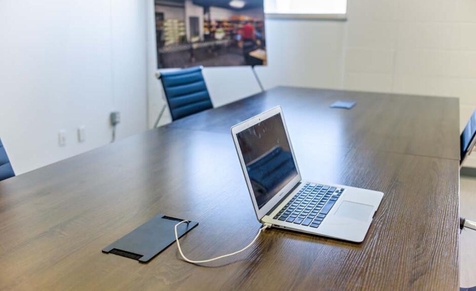 A laptop is sitting on a table in a conference room.