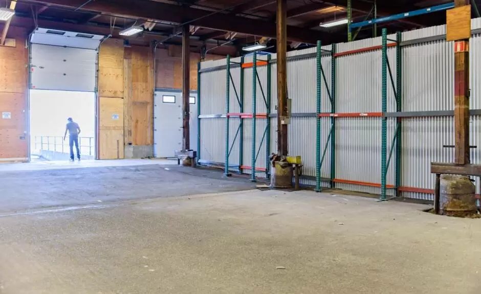 An empty warehouse with a man standing in the doorway.