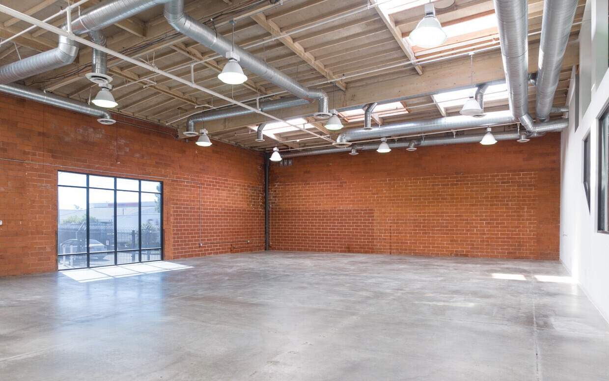 An empty room with red brick walls and a large window.