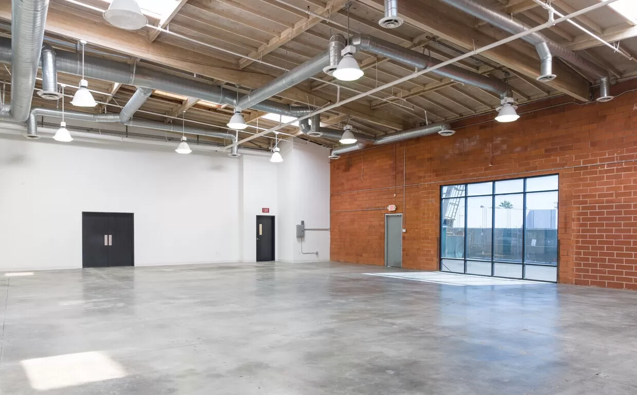 An empty warehouse with brick walls and a glass door.