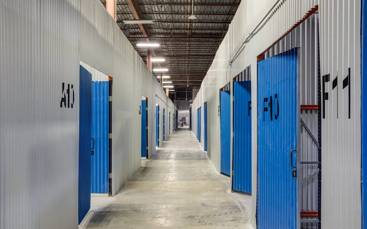 A long hallway with blue doors in a storage facility.